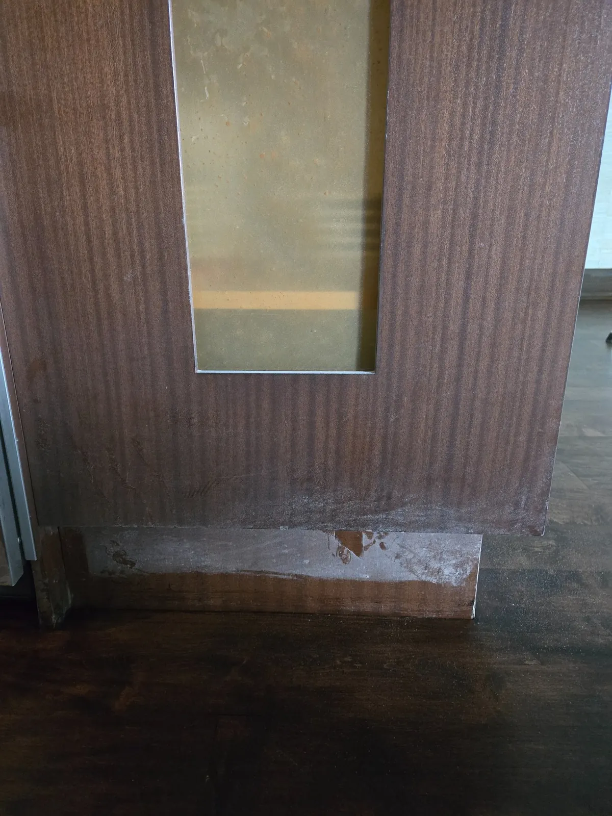 Cabinet base showing fine construction dust accumulation along the lower edge and floor junction