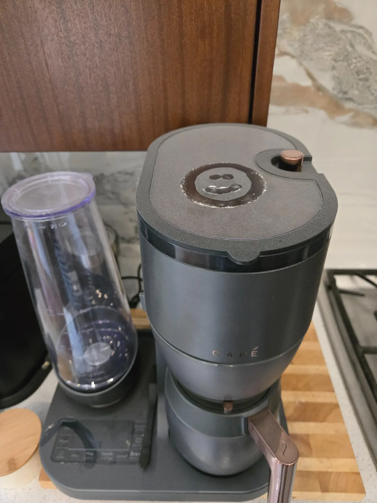 Coffee maker covered in fine construction dust with a smiley face drawn in the dust on the surface