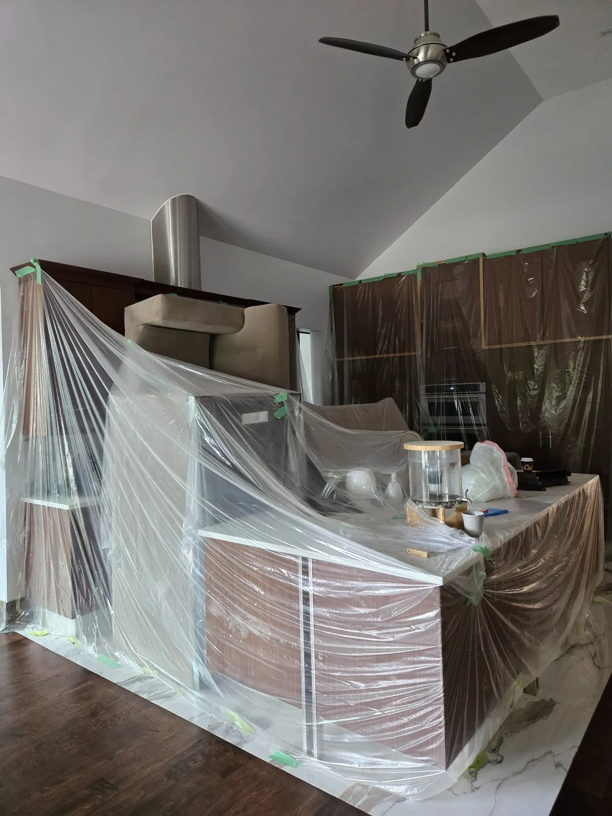Kitchen furniture covered in protective plastic sheeting before after-renovation cleaning