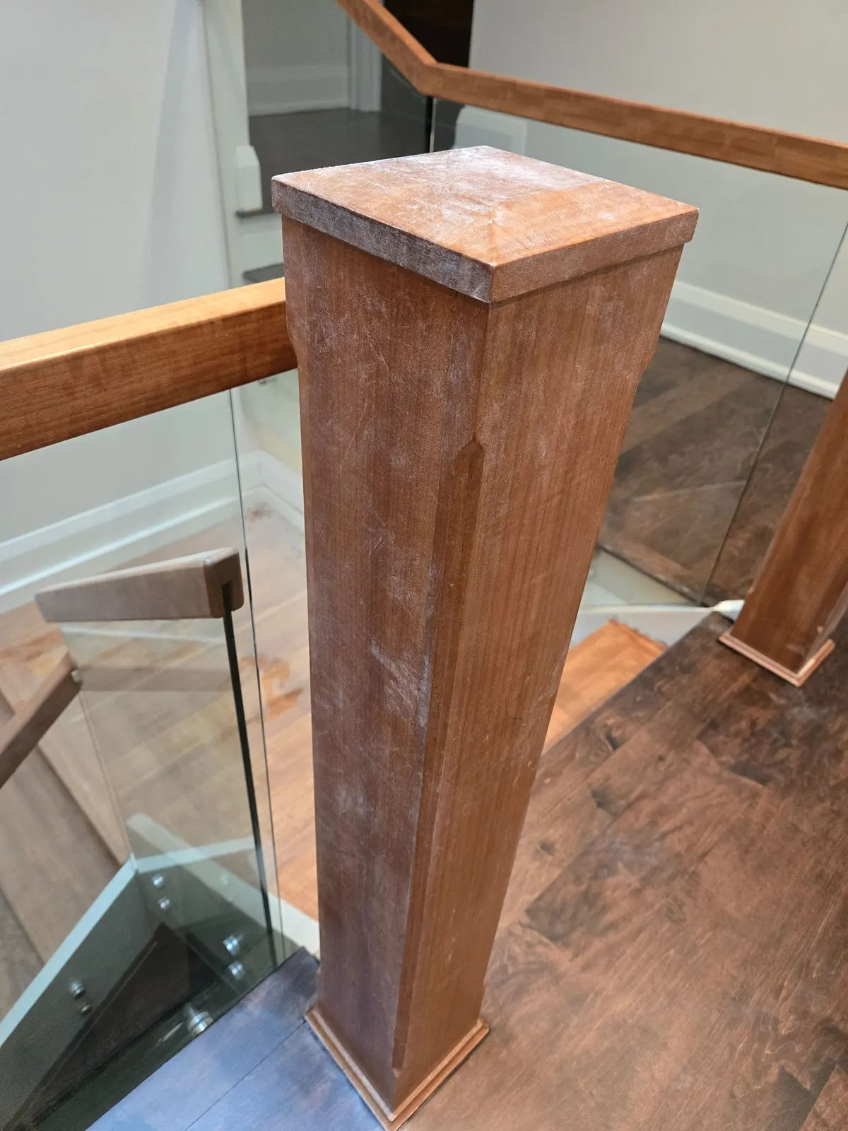 Stair post with fine construction dust visible on the post surface and surrounding detail areas